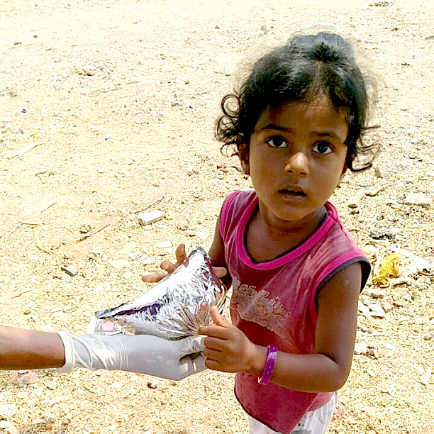 A child being handed a food pack by a Hill of Hope volunteer.