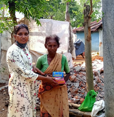 A volunteer in West Bengal handing supplies to a woman.