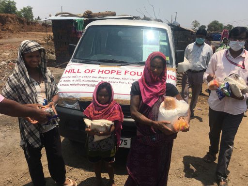 People showing the supplies they have received, standing in front of a Hill of Hope Foundation van.