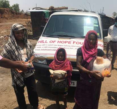 A photograph of a family, in front of the food distribution vehicle, holding the rations they have been given.